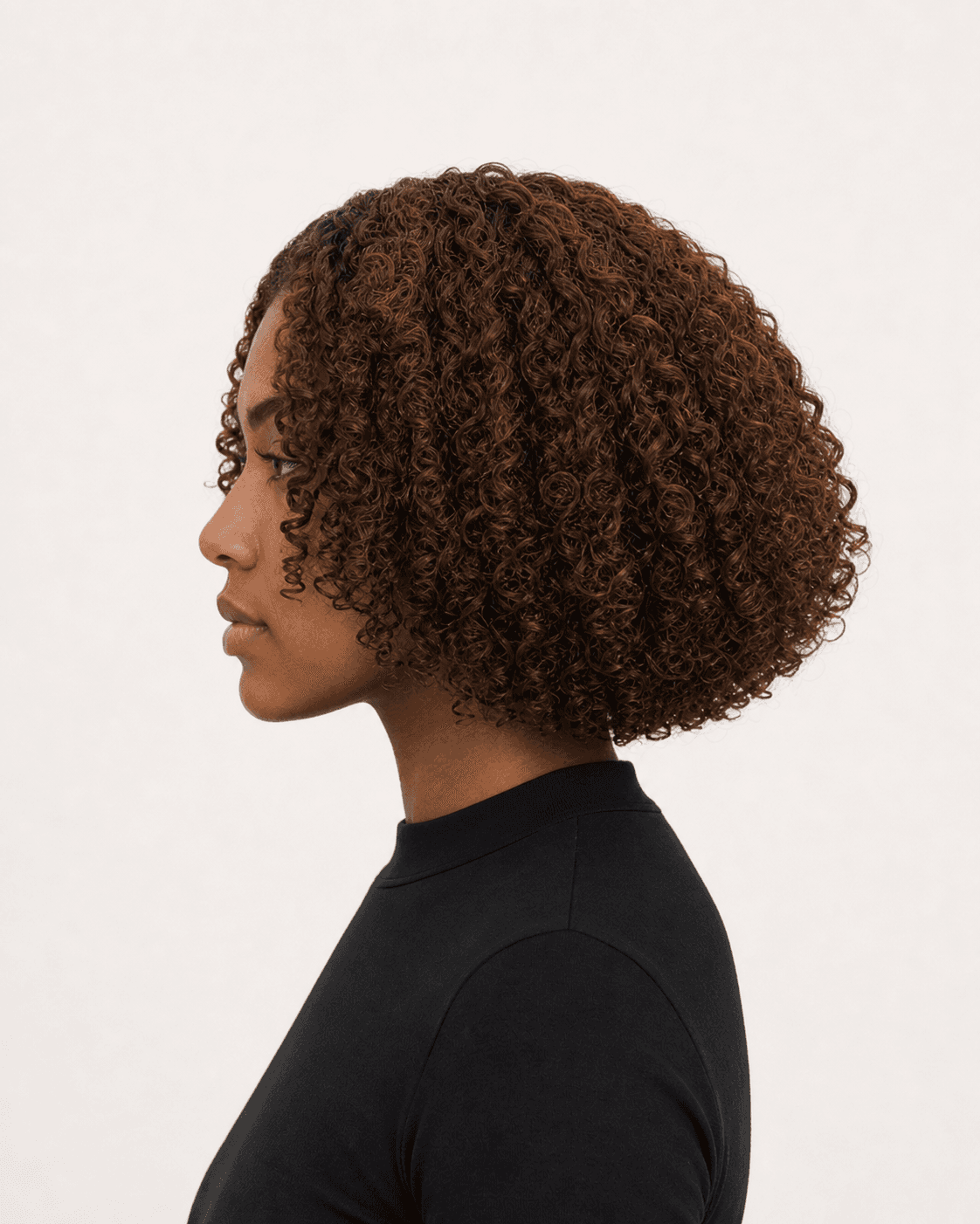 Side profile of a rounded curly bob showing crown lift and upper-neck perimeter